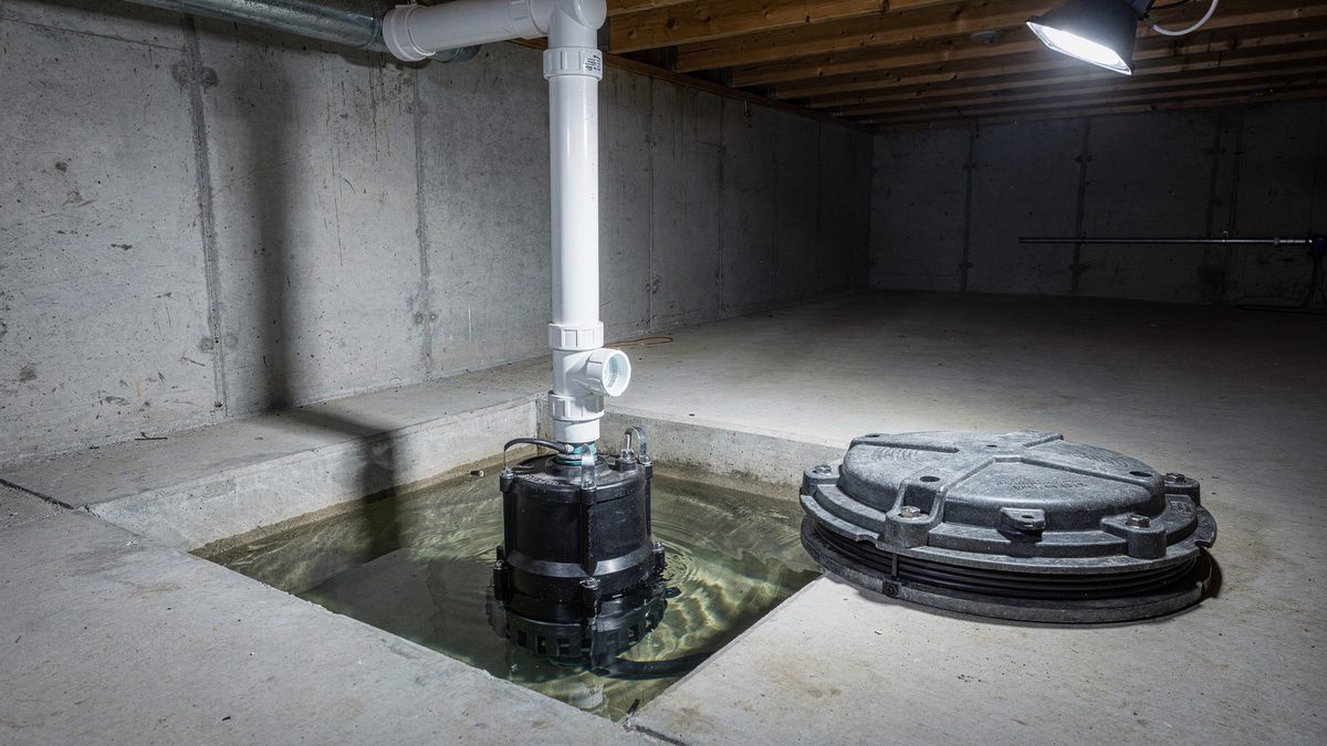 Sump pump and discharge line in an unfinished poured-concrete basement, the interior end of a perimeter drainage system